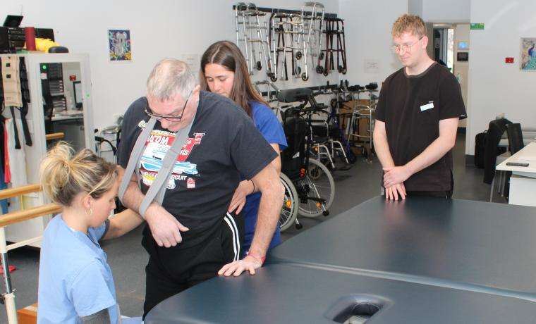 Stroke patient Keith Chaplin undergoes rehabilitation in the gymnasium at Armitage House at Wonthaggi Hospital with Physiotherapists Maddy Smith, left, and Baylie McGain, watched by Stroke Coordinator Luke Anstey.