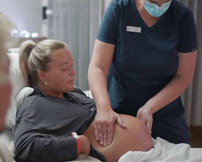 A midwife performs an abdominal palpation