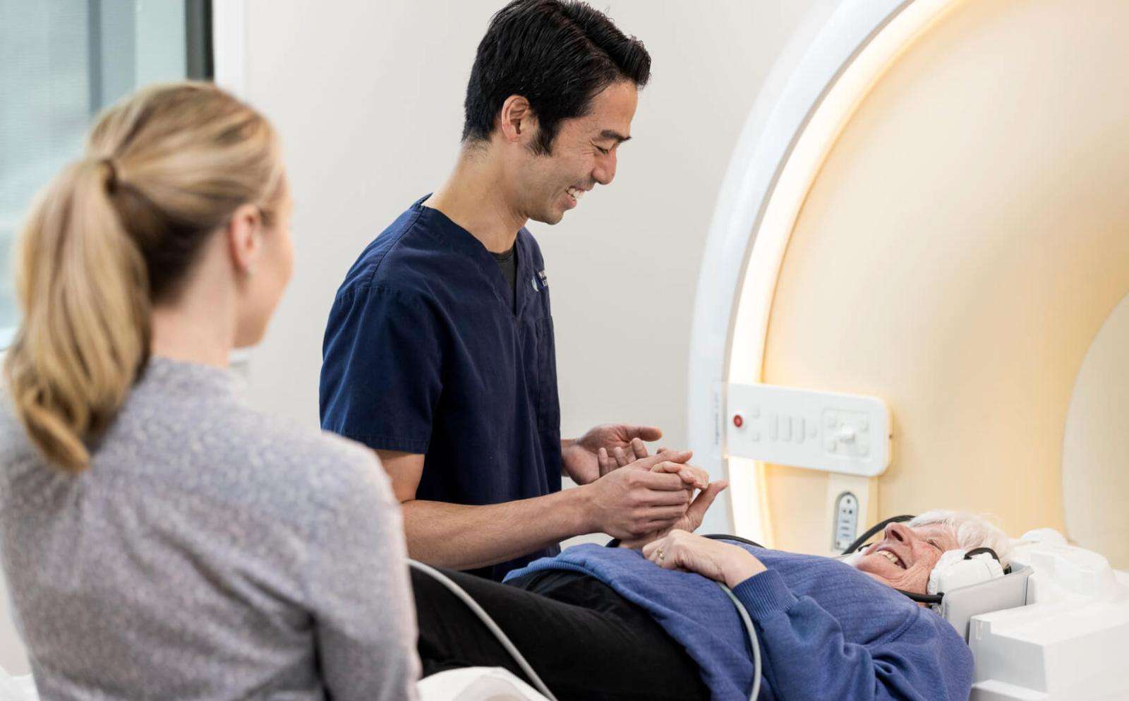 Patient on a CT bed with two staff preparing them for a CT scan